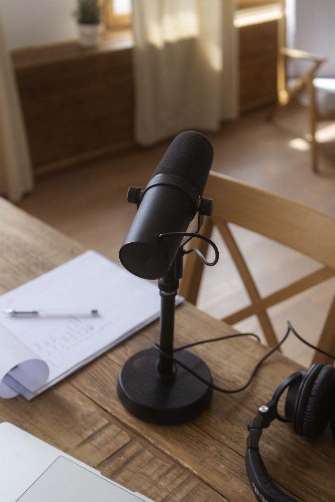 A high-quality close-up of a sleek, modern microphone on a boom arm, set against a clean desk with warm, ambient lighting, representing a professional yet accessible setup for content creators