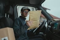 Delivery worker examining packages inside a van, focused on logistics.